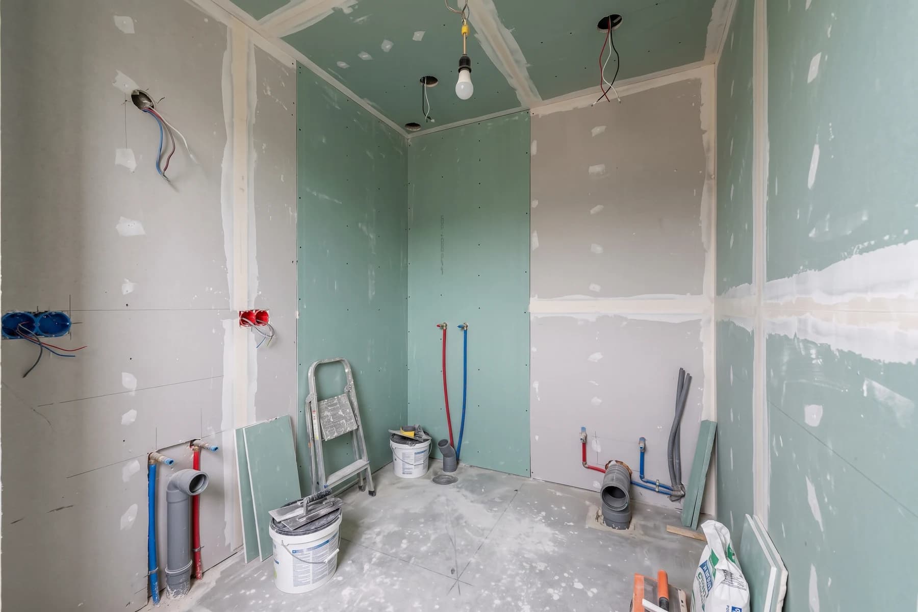 Salle de bains avant rénovation, avec cloisons et canalisations apparentes